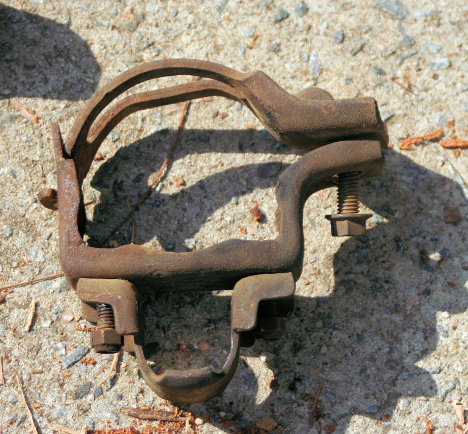 Rusty metal suspension clamp with bolts on concrete
