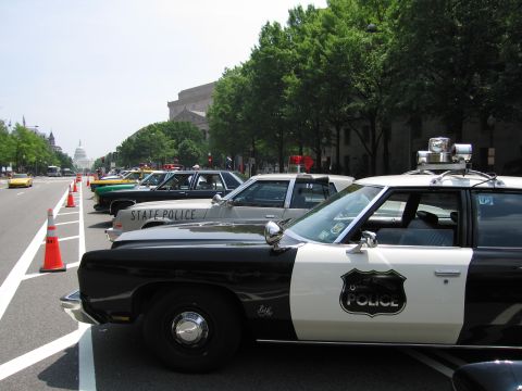 1991 Ford Crown Victoria - Several police cars are parked in a line on a street, with the Capitol building visible in the distance.