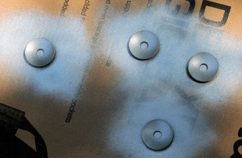 1976 Ford Ranchero - Washers are being spray painted silver on a surface with printed text.