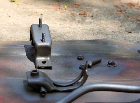 1976 Ford Ranchero - Several metal automotive parts, including engine mounts and fasteners, are laid out on a surface.