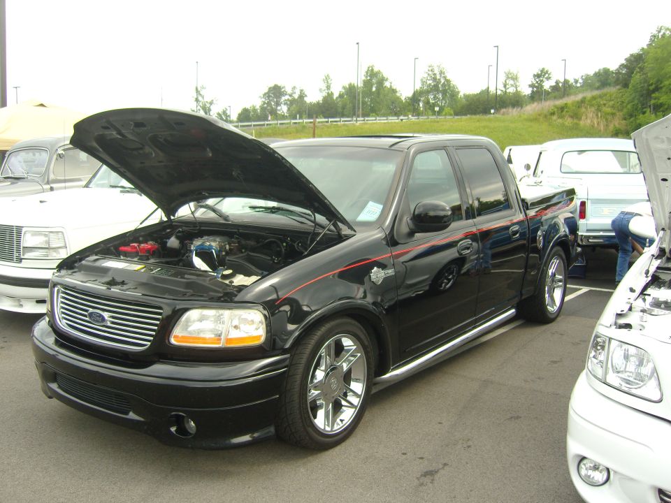 Black Ford F-150 pickup truck with hood open, chrome wheels, and red pinstripes