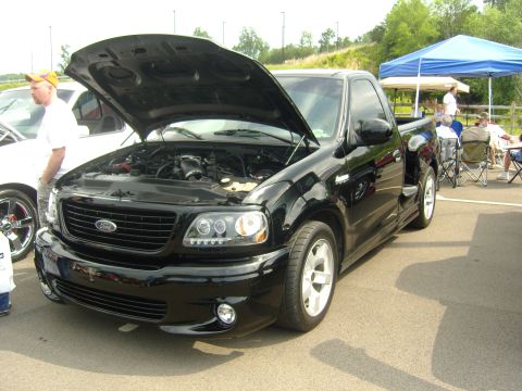 2007 Ford Mustang - Black Ford F-150 Lightning pickup truck with hood open, parked outdoors at an event.