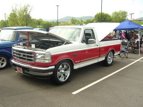 2007 Ford Mustang - White and red Ford F-150 pickup truck with hood open at an outdoor event.