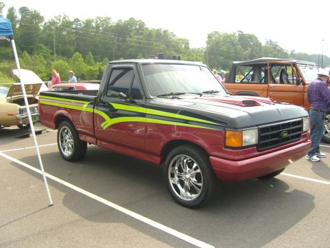 2007 Ford Mustang - A customized Ford F-150 pickup truck is displayed at an outdoor event, parked next to other vehicles.