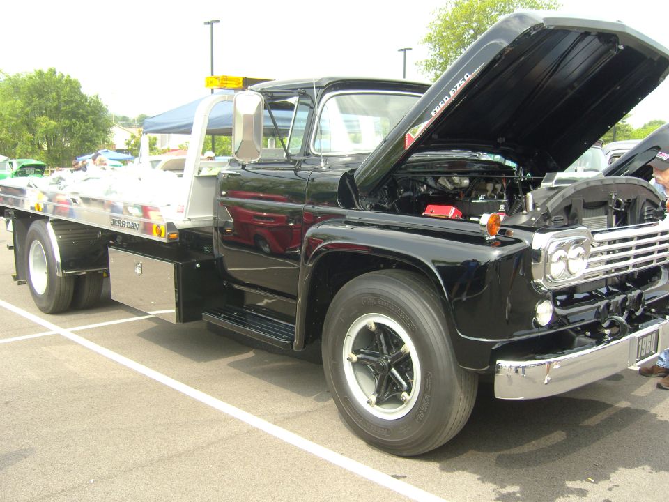 Black 1957 Ford F-series tow truck, hood open, showing engine