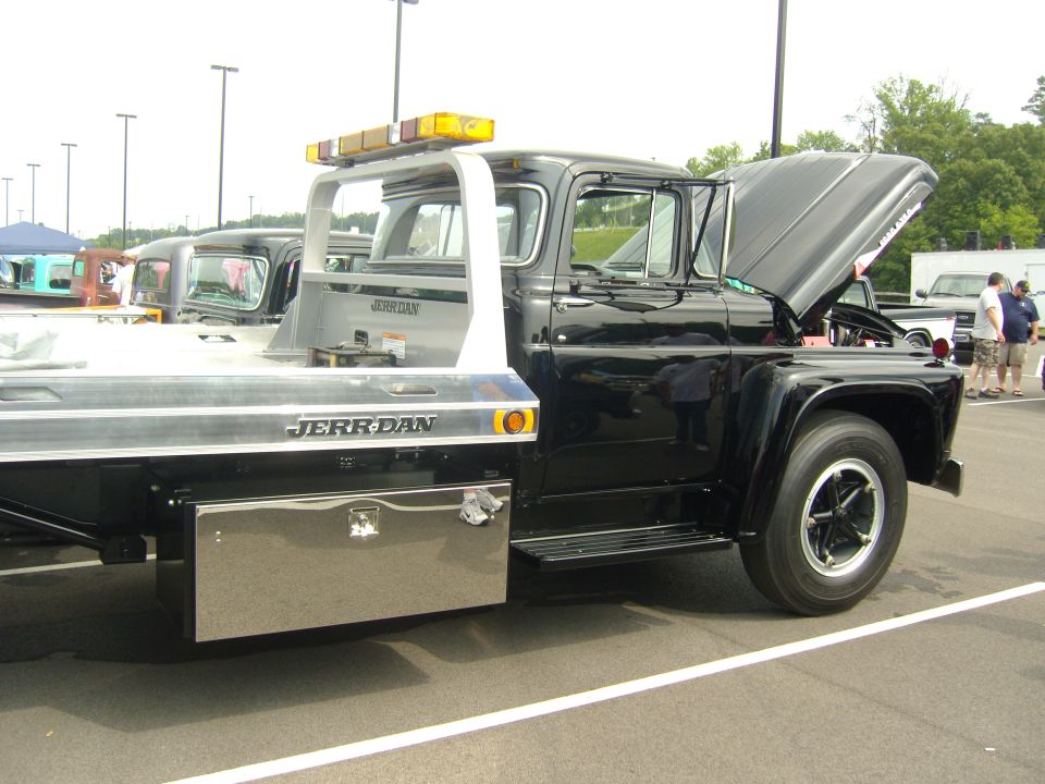 Black tow truck with JERR-DAN body, hood open. Another truck is visible behind it