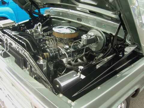 2007 Ford Mustang - The engine bay of a classic truck features a polished chrome air cleaner and custom exhaust headers, with a blue vehicle visible in the bac…