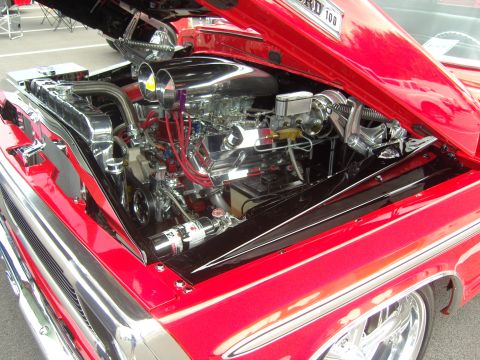 2007 Ford Mustang - Customized engine bay of a red Ford F-100 truck, polished chrome components and a powerful V8 engine.