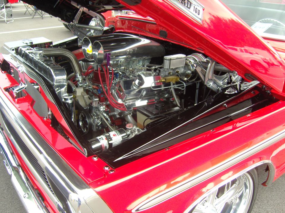 Red Ford F-100 engine bay with chrome details and dual carburetors