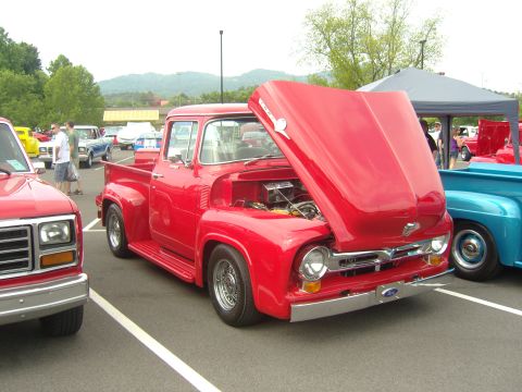 2007 Ford Mustang - A classic red Ford pickup truck is displayed with its hood up at an outdoor car show.