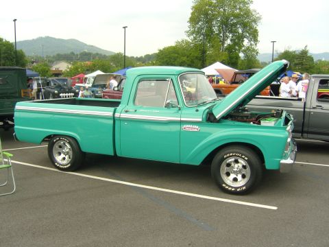 2007 Ford Mustang - A turquoise 1956 Ford F-100 pickup truck is displayed with its hood open at a car show.