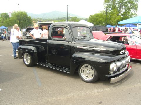2007 Ford Mustang - A black 1948 Ford F-series pickup truck is parked at an outdoor event, with other vehicles visible in the background.