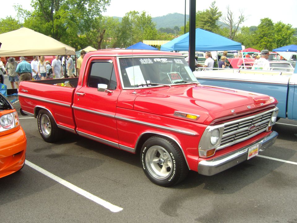 Red pickup truck with chrome grille and trim, parked at an outdoor event