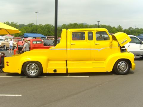 2007 Ford Mustang - Custom yellow pickup truck with extended cab and long bed, seen at an outdoor event.