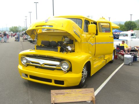 2007 Ford Mustang - A bright yellow custom truck, possibly a 1954 Ford C-500, is displayed with its hood open at an outdoor event.