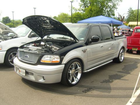 2007 Ford Mustang - A modified Ford F-150 Lightning pickup truck is displayed with its hood open at an outdoor event.