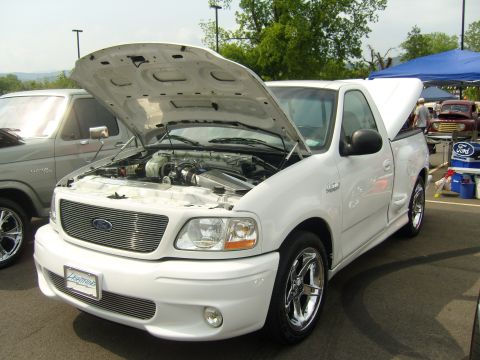 2007 Ford Mustang - White Ford F-150 Lightning pickup truck with hood open at an outdoor event.