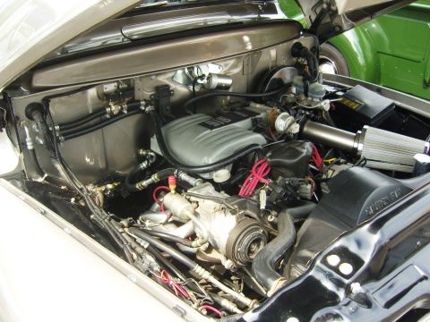 2007 Ford Mustang - The engine bay of a vehicle, a silver intake manifold and an exposed air filter, with another vehicle visible in the background.