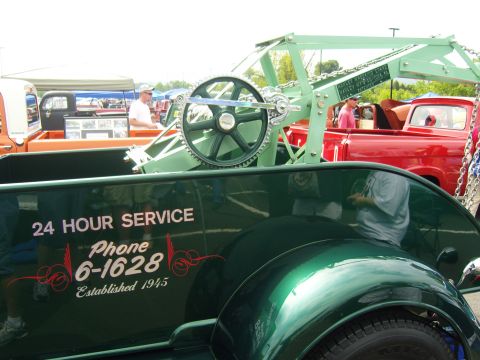 2007 Ford Mustang - A vintage green tow truck with a crane is parked next to a red pickup truck at an outdoor event.