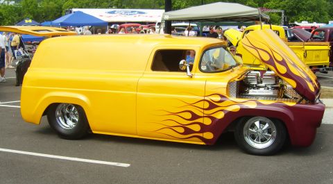 2007 Ford Mustang - A custom yellow panel van with flame graphics is displayed at an outdoor event with other vehicles and tents.