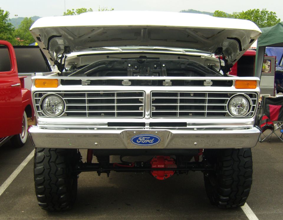 White Ford truck front view, hood open, chrome grille, Ford badge