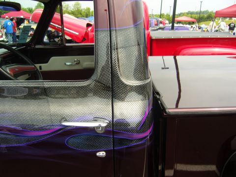 2007 Ford Mustang - A custom pickup truck with a unique carbon fiber wrap and flame graphics is displayed at an outdoor event.
