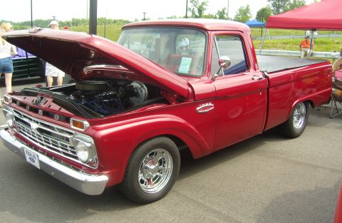 2007 Ford Mustang - A classic red Ford F-100 pickup truck is displayed with its hood open, revealing the engine bay.