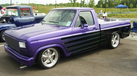 2007 Ford Mustang - A custom purple pickup truck is parked next to a blue truck at an outdoor event.