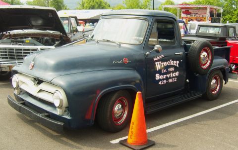 2007 Ford Mustang - Dark blue mid-1950s Ford F-100 stepside pickup with white bar grille, hand-lettered 'Walker's Wrecker Service Est. 1969' door signage and a…