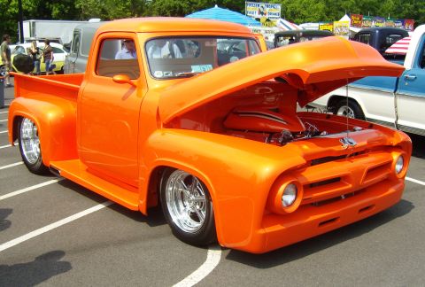 2007 Ford Mustang - A custom orange 1956 Ford F-100 pickup truck is displayed with its hood open at an outdoor event.