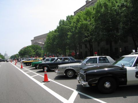 1991 Ford Crown Victoria - Several vintage police cars are lined up on a street, with the U.S. Capitol building visible in the background.