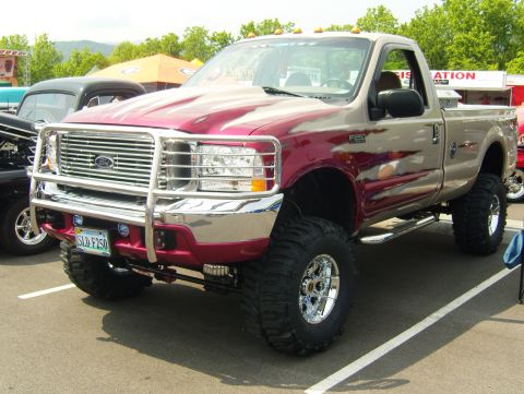 2007 Ford Mustang - This lifted pickup truck features a two-tone paint job with flame graphics and a prominent chrome grille guard.