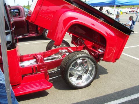 2007 Ford Mustang - Custom red pickup truck with bed raised, revealing its chassis and suspension system.