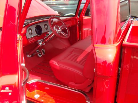 2007 Ford Mustang - The custom interior of a red pickup truck features red leather seats and a polished steering wheel.