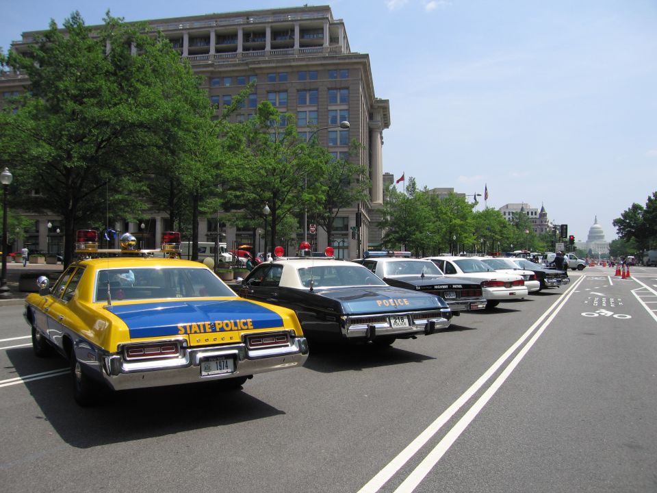 Yellow State Police car leading a row of cruisers toward the Capitol