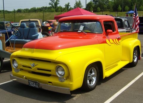2007 Ford Mustang - A two-tone 1956 Ford F-series truck with custom flames is parked at an outdoor event.