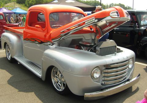 2007 Ford Mustang - Customized Ford F-series pickup truck with a two-tone silver and orange paint scheme and flame graphics, displayed with its hood open.