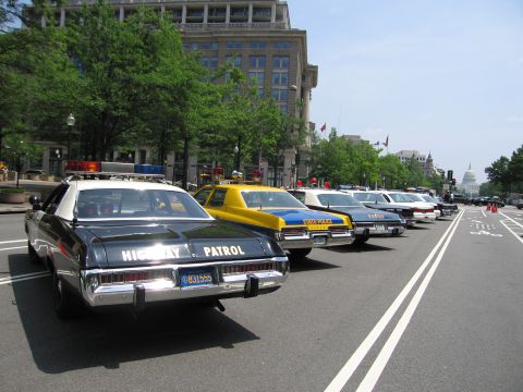 1991 Ford Crown Victoria - Several police cars, including a highway patrol unit, are parked in a row on a city street.