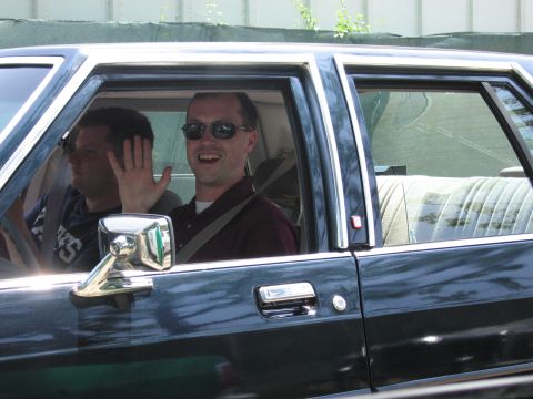 1991 Ford Crown Victoria - A man waves from the passenger seat of a dark blue 1991 Ford Crown Victoria.