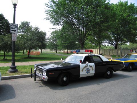 1991 Ford Crown Victoria - A vintage police car with a light bar is parked next to another police vehicle.