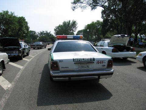 1991 Ford Crown Victoria - A 1991 Ford Crown Victoria police car is seen from the rear, equipped with a light bar and sheriff markings.
