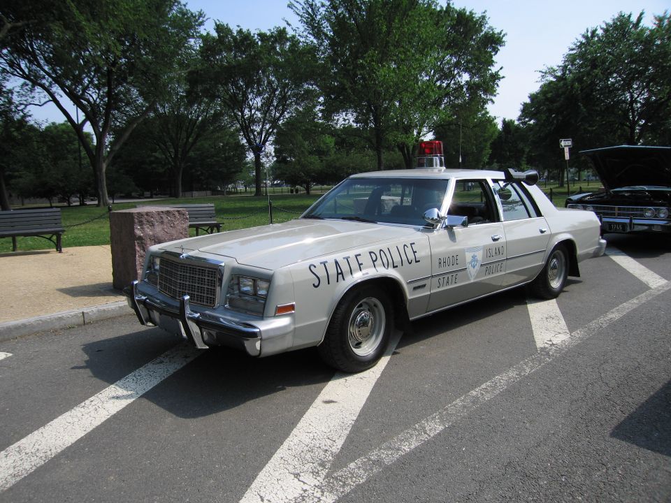 Silver Chrysler State Police sedan parked in a grassy park