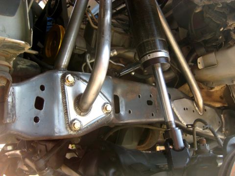 1996 Ford Bronco - Close-up view of aftermarket suspension modifications on a vehicle's frame.