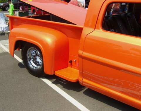 2007 Ford Mustang - The rear quarter panel and bed of a custom orange pickup truck are visible, flame graphics on the door.