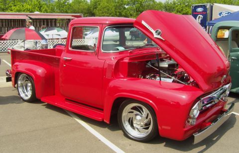2007 Ford Mustang - A bright red 1956 Ford F-100 pickup truck is displayed with its hood open, revealing the engine compartment.