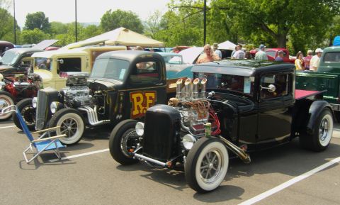 2007 Ford Mustang - A pair of customized pickup trucks with prominent engines are displayed at an outdoor event.