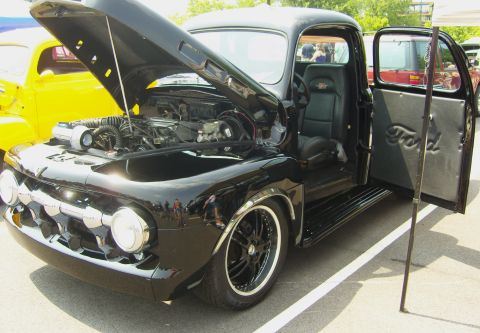 2007 Ford Mustang - A custom black Ford pickup truck is displayed with its hood and driver's door open, revealing the engine and interior details.