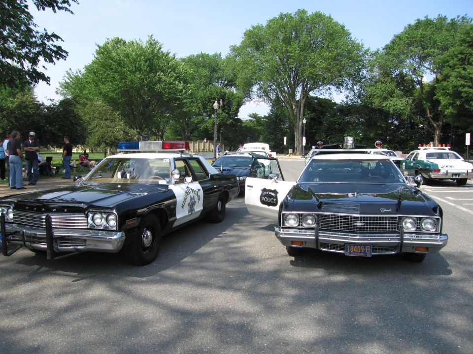 Black-and-white Dodge patrol car beside a black Chevrolet patrol car