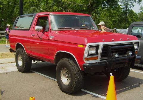 2007 Ford Mustang - A red 1978 Ford Bronco is parked next to another vehicle at an outdoor event.