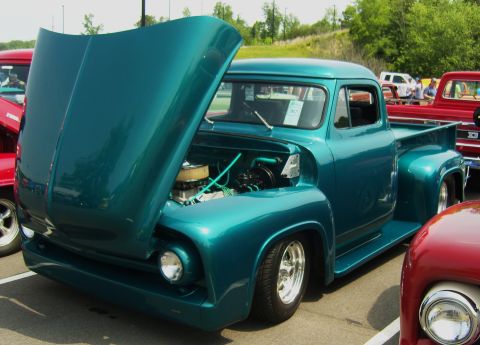 2007 Ford Mustang - Teal 1956 Ford F-100 pickup truck with hood open at a car show.